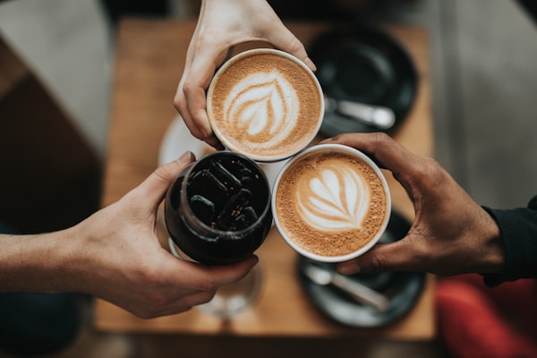 Three hands holding coffee cups together at dawn